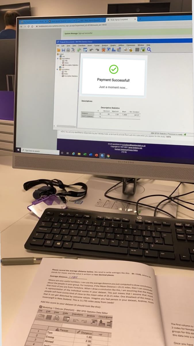 Computer displaying a payment confirmation beside a keyboard and printed materials
